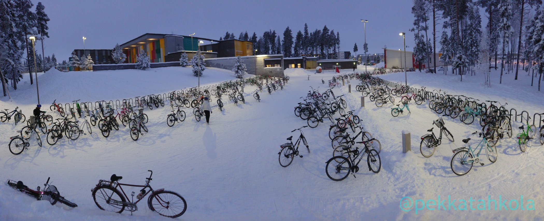 Hundreds of kids' bicycles parked at a schoolyard in snowy winter conditions.